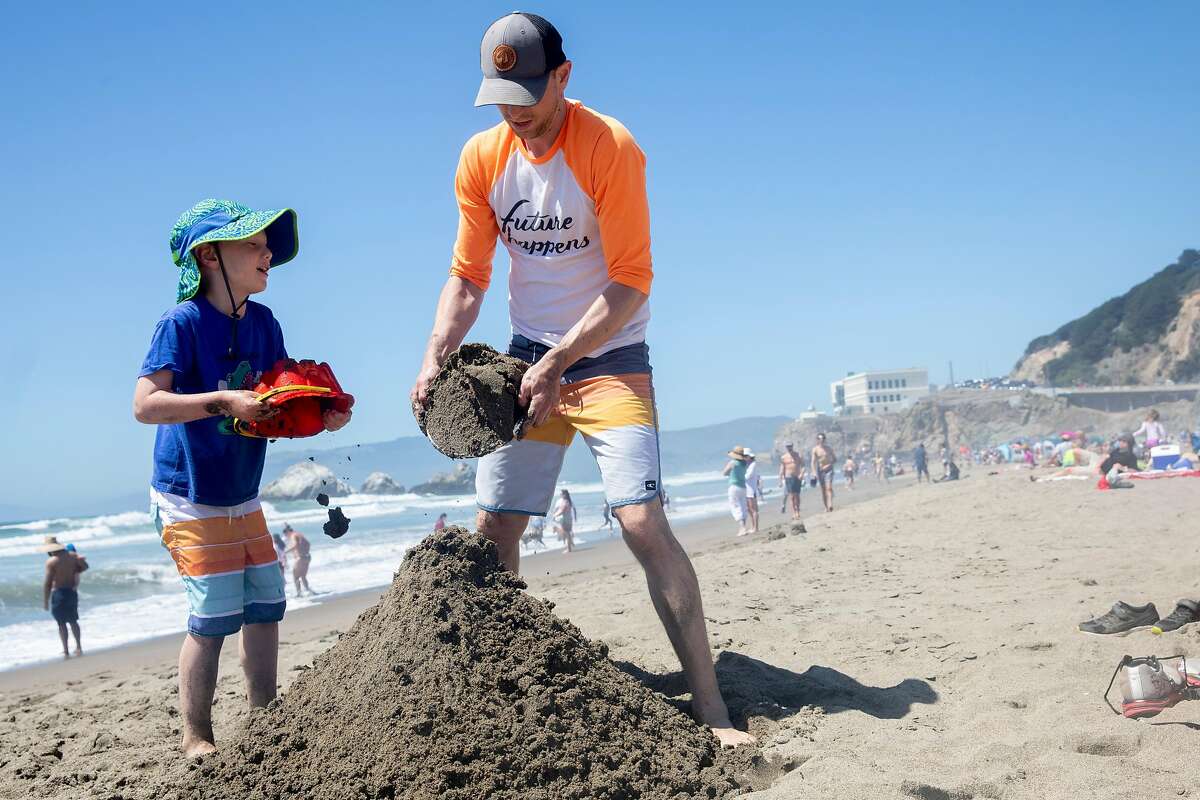 Kevin Albert of San Francisco helps his son Zeki, 5, build a sandcastle while enjoying Ocean Beach in San Francisco, Calif. Monday, May 25, 2020. The warm Memorial Day weather brought out large crowds to popular parks and beaches despite the shelter-in-place order amid the COVID-19 pandemic.