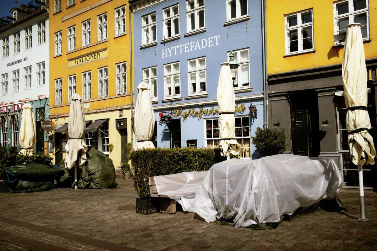 Terrace tables stand covered outside closed restaurants in the popular tourist location of Nyhavn Harbour in Copenhagen on April 15, 2020.