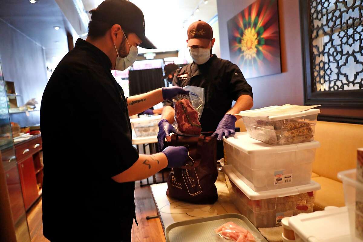 Canela's Chris Munoz (left) and chef Mat Schuster construct a butcher bag at the restaurant on Market Street in San Francisco, Calif., on Sunday, May 24, 2020.