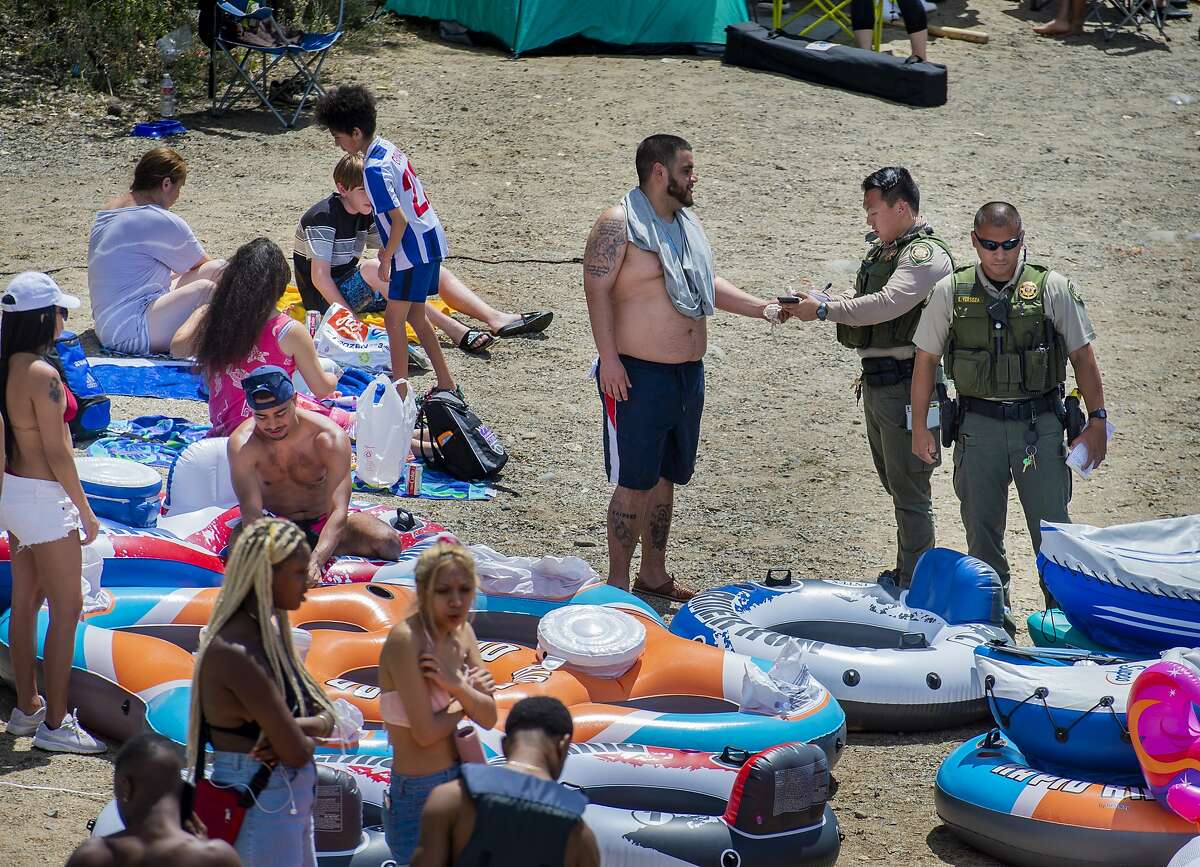 A Sacramento County park ranger issues an alcohol citation to an American River visitor in the Sunrise Recreation Area near Rancho Cordova, Calif., during the Memorial Day weekend, Sunday, May 24, 2020. Alcohol is banned along the shoreline of the river between Hazel and Watt avenues on Memorial Day weekend, the Fourth of July and Labor Day weekend. (Daniel Kim/The Sacramento Bee via AP)
