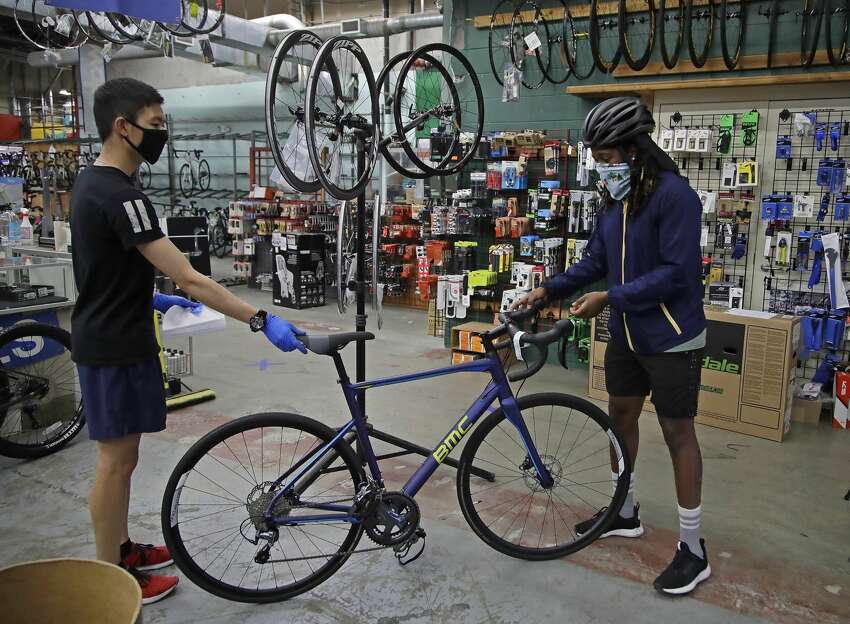 In this Friday, May 15, 2020 photo, Joel Johnson, right, takes delivery of his new bicycle at the Sports Basement store in San Francisco. Johnson hadn't owned a bicycle since he was 15, but soon after the coronavirus pandemic led to a shelter in place order in San Francisco, he bought a bike to avoid crowded public trains and buses. He is among thousands of cooped-up Americans snapping up new bicycles or dusting off decades-old bikes to stay fit, keep their mental sanity or have a safe alternative to public transportation.