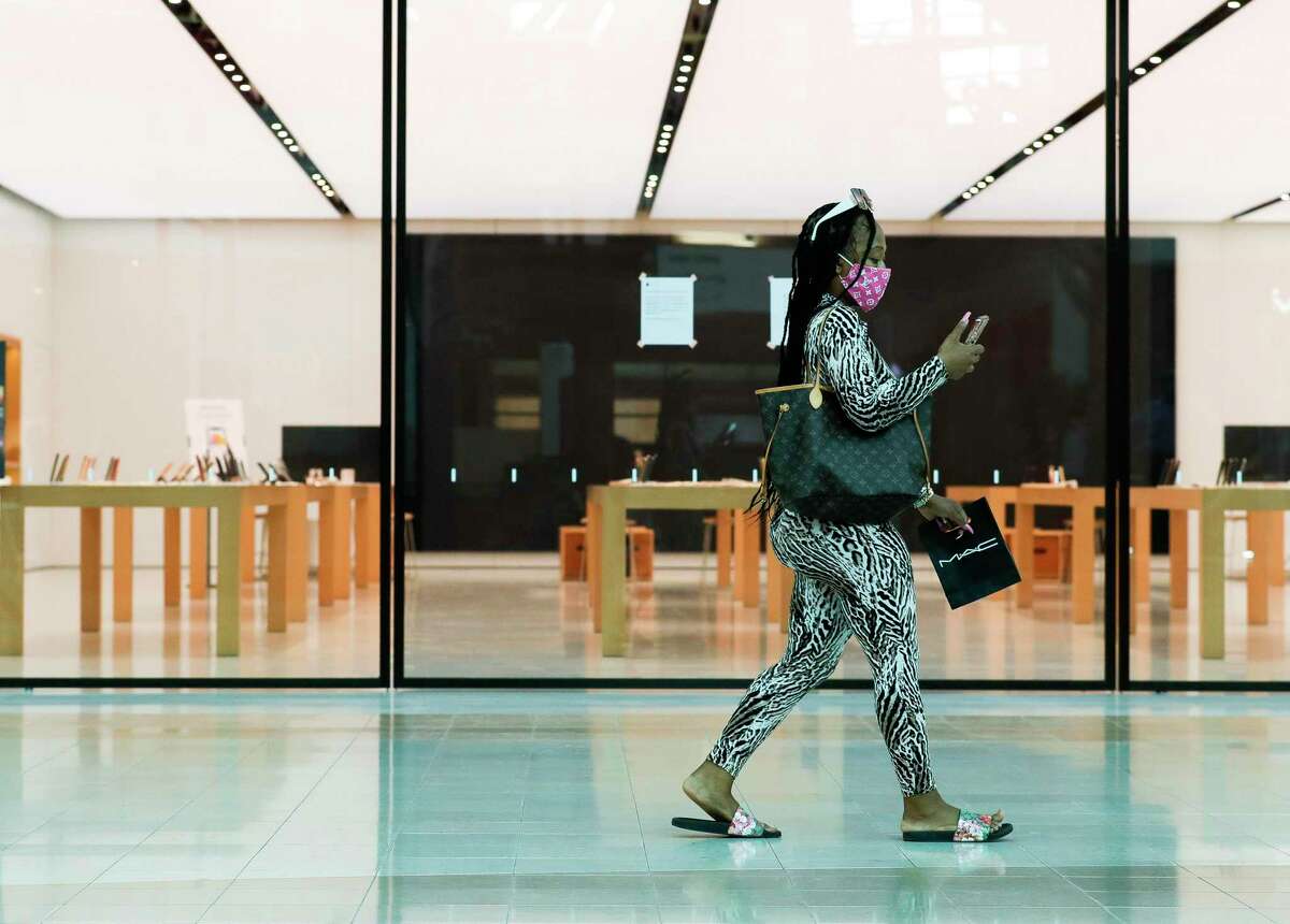 Shoppers wearing a mask walks past the Apple store at The Woodlands Mall, Tuesday, May 5, 2020, in The Woodlands. The Woodlands Apple Store, along with all the Houston-area Apple retail outlets, will reopen with limited hours starting Wednesday.