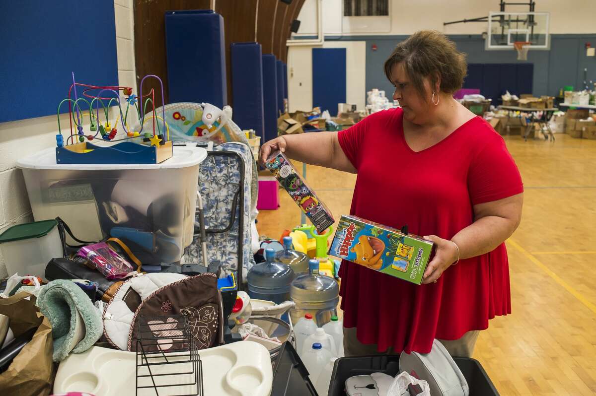 Lisa Taglauer chooses toys for a young boy as she volunteers at a donation drive providing residents affected by flooding with toiletries, cleaning supplies, food items, toys, pet supplies and much more at Meridian Elementary Tuesday, May 26, 2020. (Katy Kildee/kkildee@mdn.net)