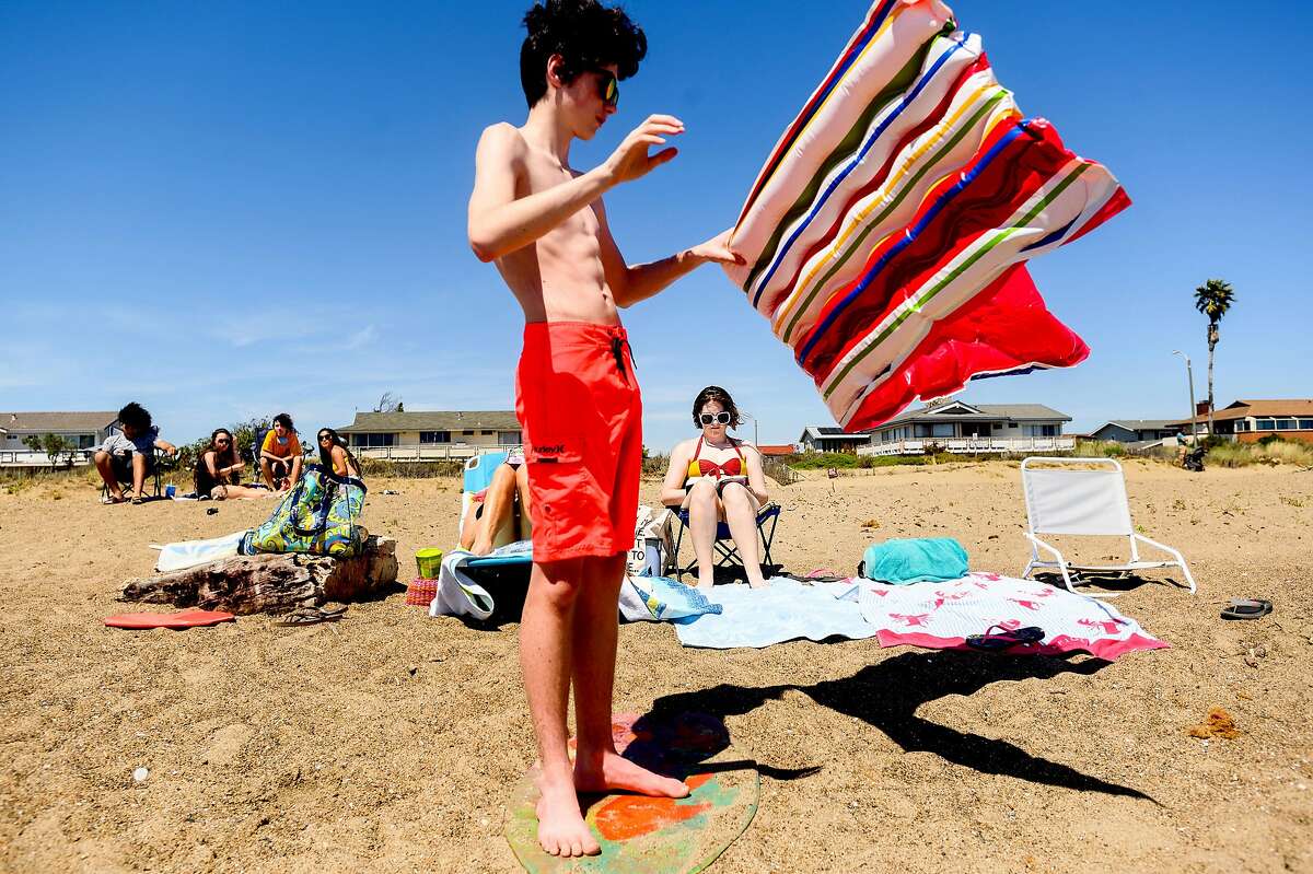 Venus Roberts, 17, reads as her brother Blazen Roberts, 14, inflates a float at Robert W. Crown Memorial Beach on Tuesday, May 26, 2020, in Alameda, Calif.