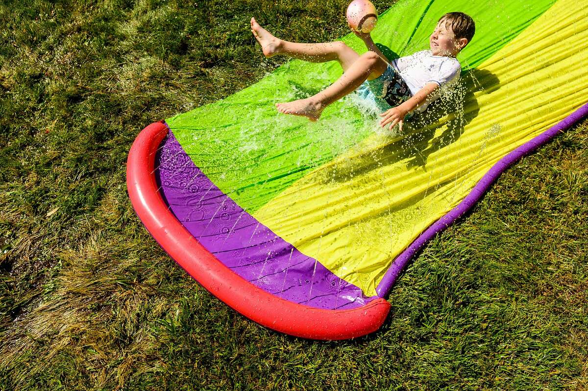 As temperatures soar throughout the Bay Area, Mason Shelby, 7, cools off on a Slip 'N Slide on Tuesday, May 26, 2020, in Alameda, Calif.