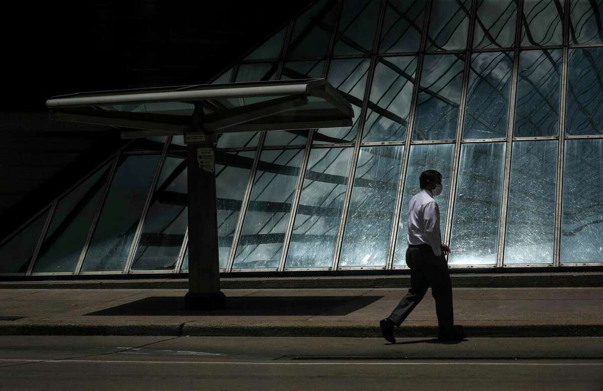 A man walks by a downtown bus stop on May 27, 2020, in Houston. Even as state officials began reopening many Texas businesses in early May, bus and rail use has continued to remain half or less of typical work days.