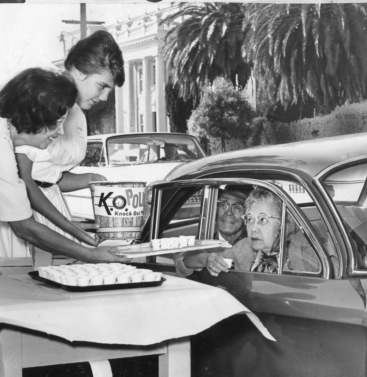 The K.O. Polio campaign would distribute millions of doses of vaccine via sugar cubes, September 1962 Dorothy Michels and Karen Merchant pass vaccine to Carmen Guerrero at a a curbside service September 29, 1962