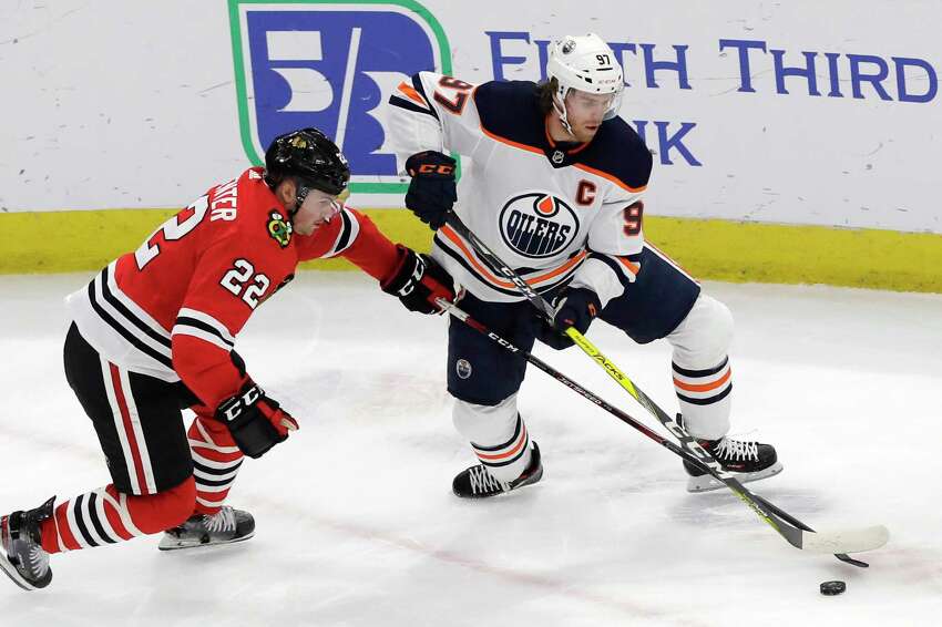 FILE - In this March 5, 2020, file photo, Edmonton Oilers center Connor McDavid, right, and Chicago Blackhawks center Ryan Carpenter vie for the puck during the first period of an NHL hockey game in Chicago. McDavid gets just his second taste of the playoffs in his fifth season. (AP Photo/Nam Y. Huh, File)