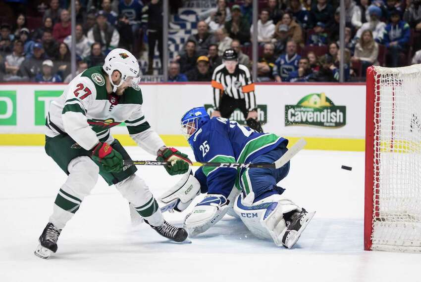 FILE - In this Feb. 19, 2020, file photo, Minnesota Wild's Alex Galchenyuk, left, scores against Vancouver Canucks goalie Jacob Markstrom, of Sweden, during the shootout in an NHL hockey game in Vancouver, British Columbia. The Canucks get Markstrom back from a knee injury, and he has had the benefit of skating at home in Sweden during the pause. (Darryl Dyck/The Canadian Press via AP, File)