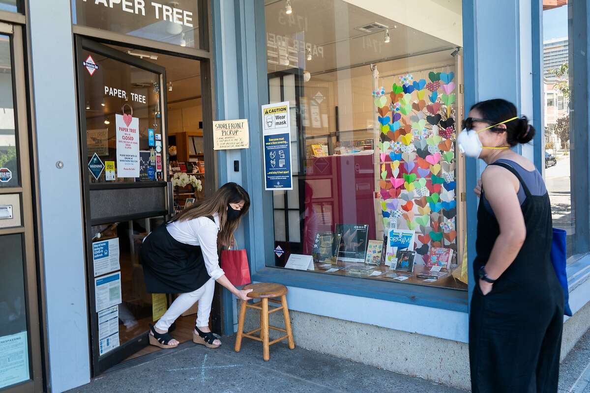 Linda Mihara, the owner of an origami shop called Paper Tree in Japantown, sets a stool to set a bag on for customer Erica Nobori on Monday, May 25, 2020, in San Francisco, Calif.