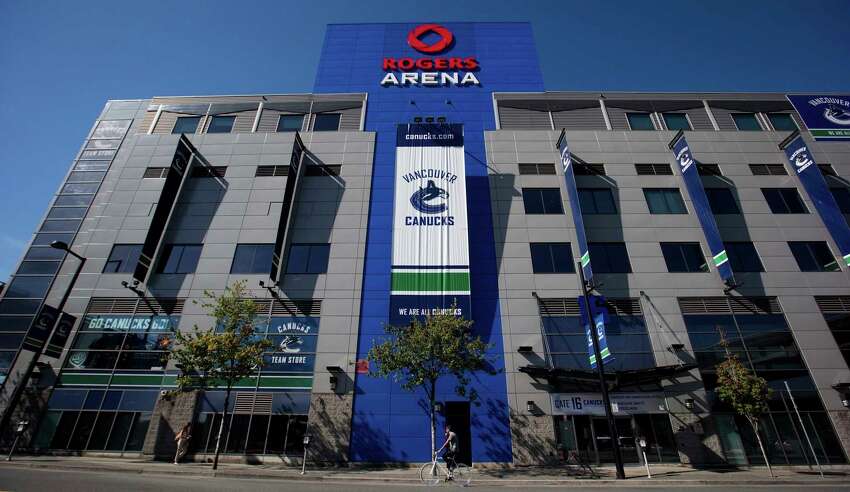 FILE - In this Sept. 16, 2012, file photo, a cyclist rides past Rogers Arena, the home of the Vancouver Canucks NHL hockey team, in Vancouver, British Columbia. Rogers Arena is one of the possible locations the NHL has zeroed in on to host playoff games if it can return amid the coronavirus pandemic. The league will ultimately decide on two or three locations for games, with government regulations, testing and COVID-19 frequency among the factors for the decision that should be coming within the next three to four weeks. (Darryl Dyck/Canadian Press via AP, File)