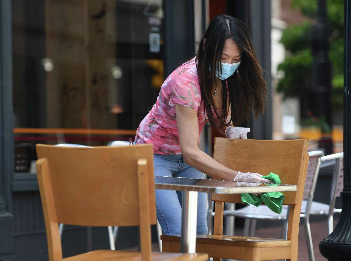 A waitress cleans a table on Wednesday, May 27, 2020, on the restaurant row of Washington Street in Norwalk, Conn.