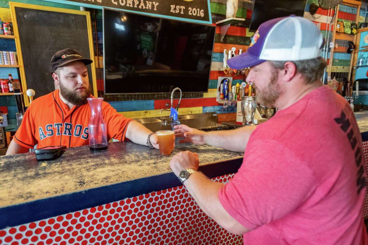 Neches Brewing Company bartender Alex Bass gives a beer to Cliff Tolbert. Friday saw the reopening of bars in Texas with limited capacity and more cleaning and sterilizing than before the Covid pandemic. Photo made on May 22, 2020. Fran Ruchalski/The Enterprise