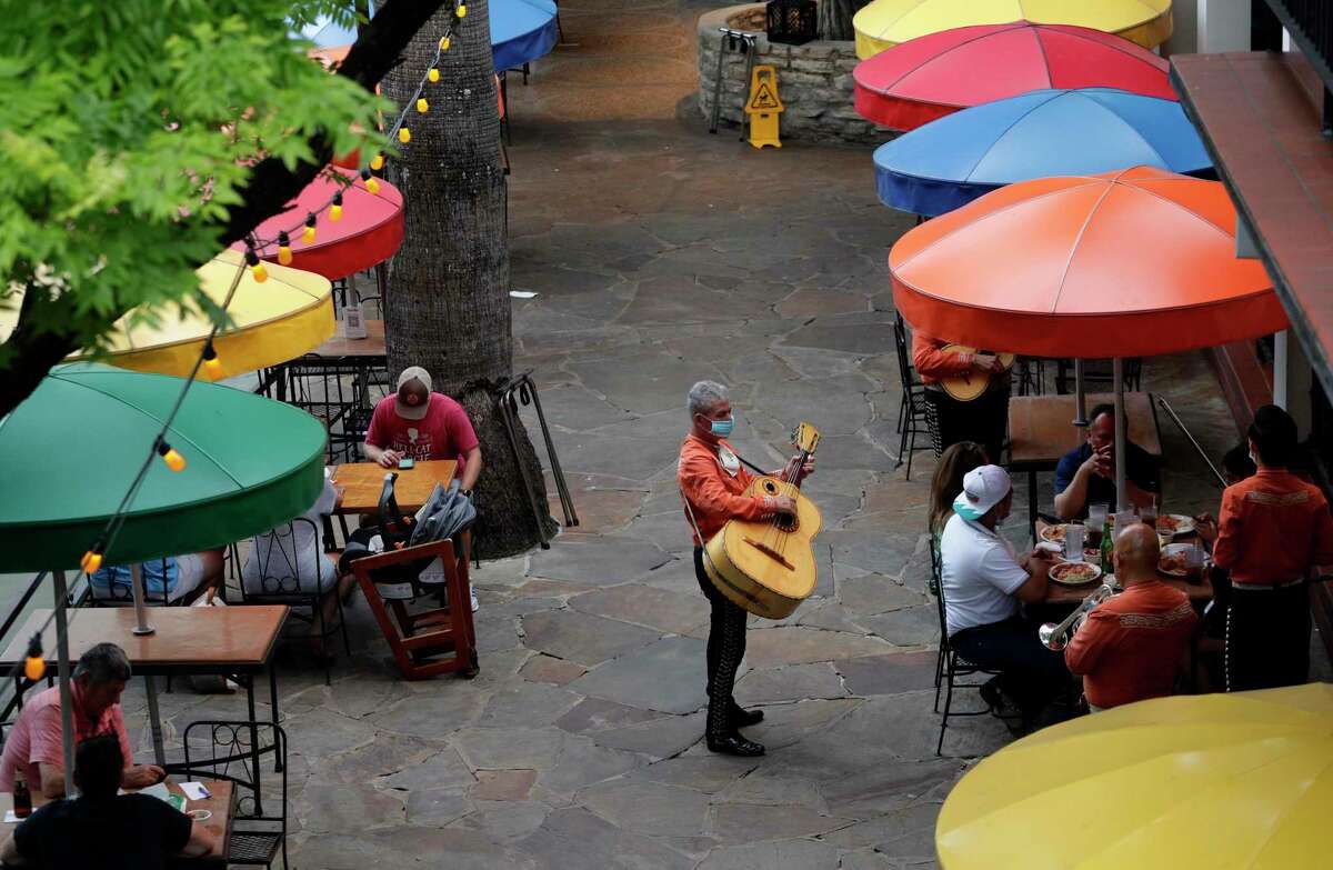 Mariachi musicians, wearing face masks, play for diners at a restaurant that has reopened to 50 percent capacity on the River Walk in San Antonio, Wednesday, May 27, 2020, as the COVID-19 pandemic lessens in the area.