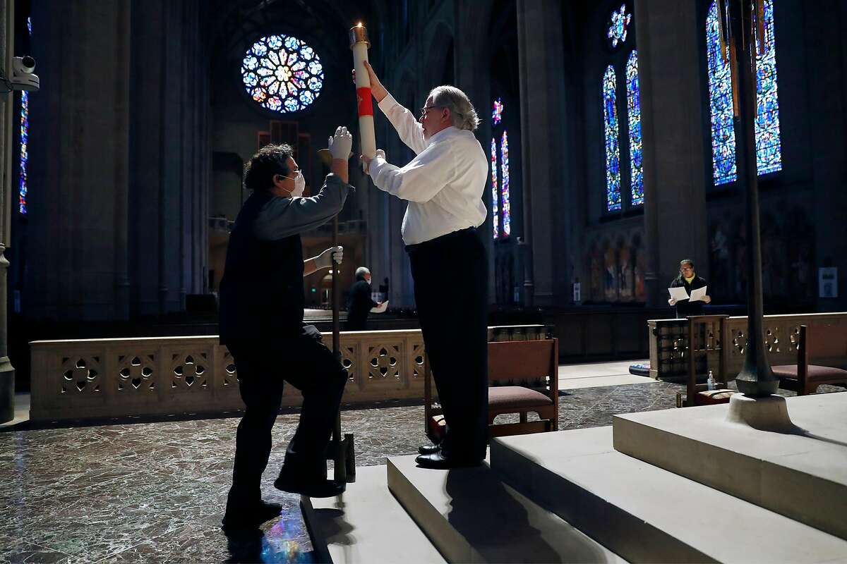 Charles Shipley (right) and John Horton place a candle before virtual Easter Sunday service at Grace Cathedral in San Francisco, Calif., on Sunday, April 12, 2020.