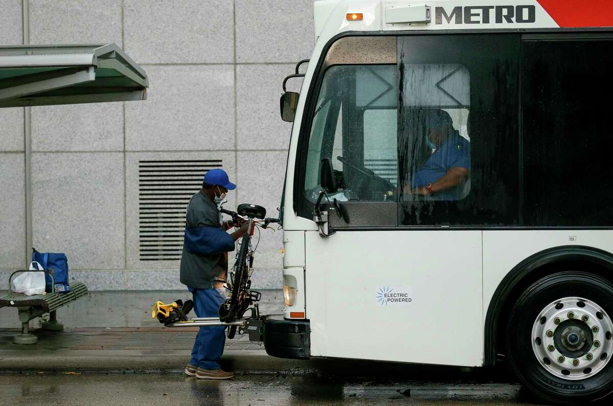 A man unloads his bicycle from the front rack of a Metropolitan Transit Authority bus, after getting off at the intersection of Travis and Polk on May 27, 2020, in Houston.