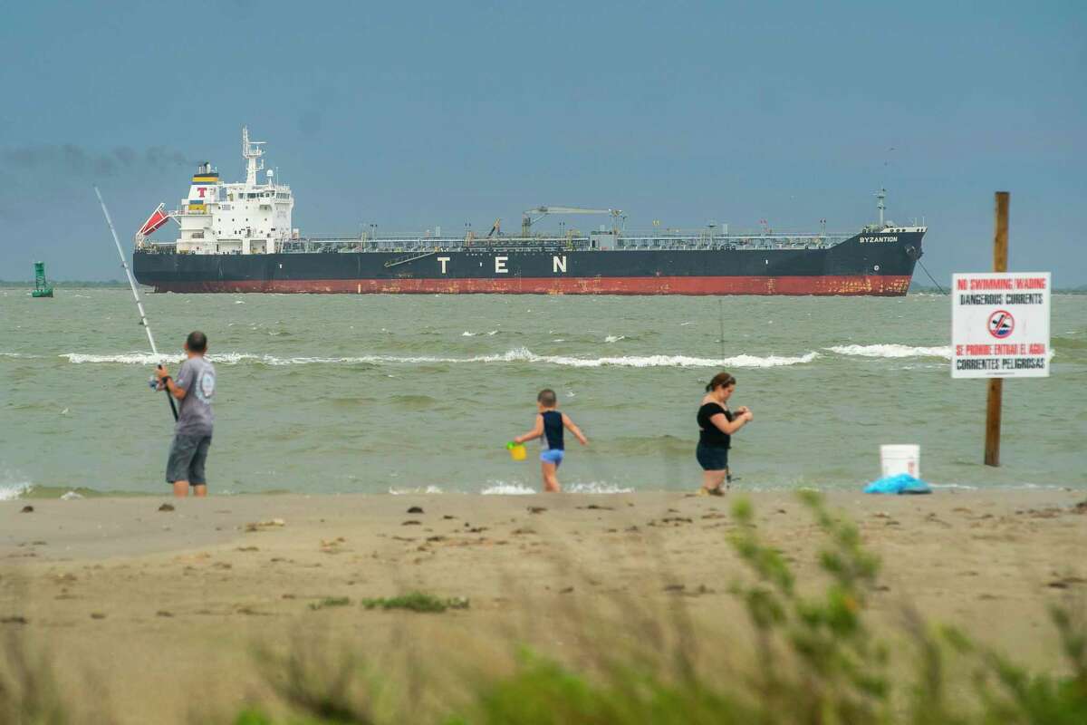 An oil tanker sits at the Bolivar Roads Anchorage between Galveston Bay and the Gulf of Mexico near people fishing, Friday, May 15, 2020, off of the east end of Galveston Island.