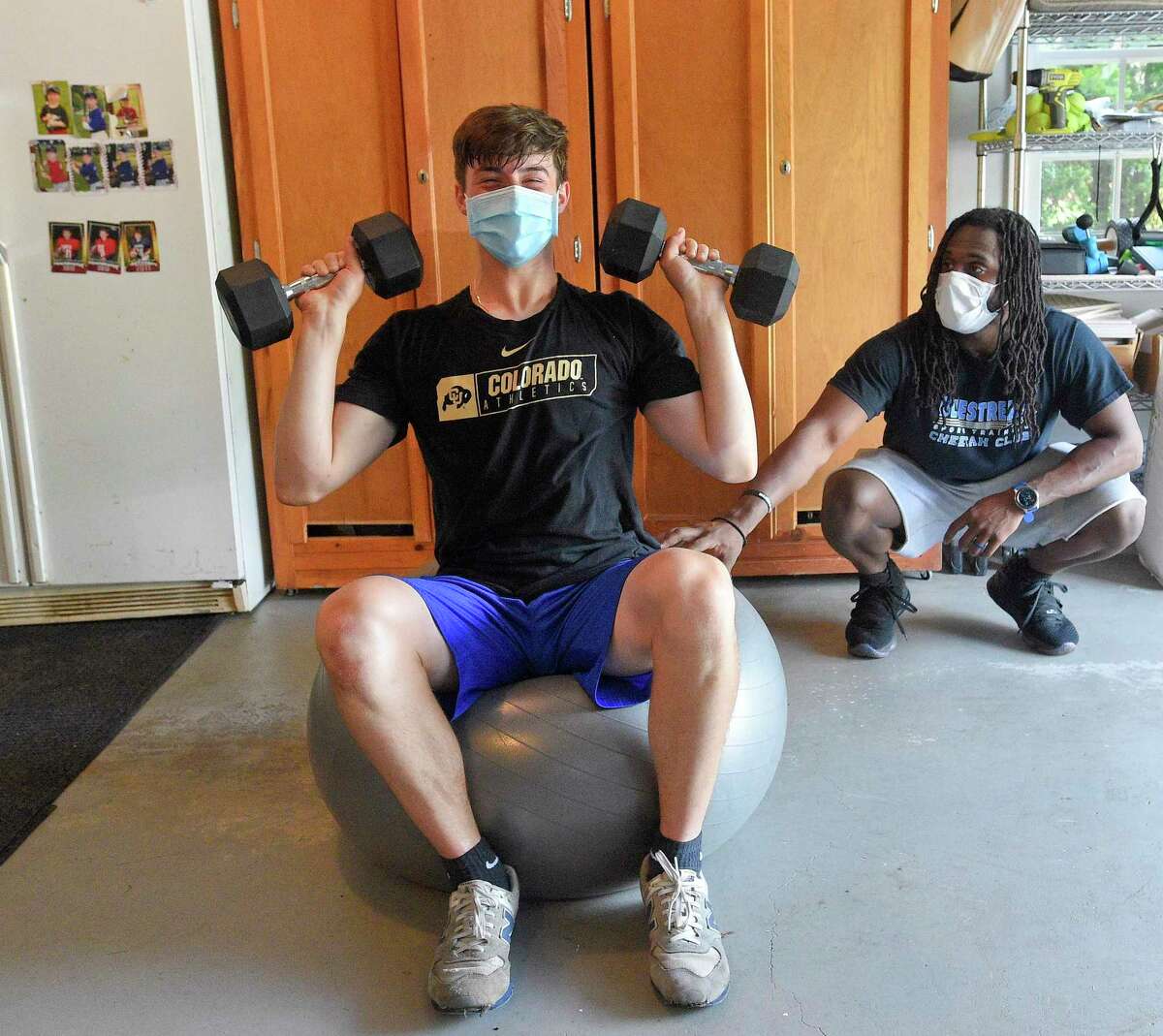 Ali Knott, at right, works with student athlete Ben Pennella, a Junior at Westhill High School at Pennella's workout studio set up in his families garage in Stamford, Connecticut on May 27, 2020. Knott, who left his position as the Strength and Conditioning coach with Westhill in the fall of 2019, to devote more time to his current employer BlueStreak Sports Training of Stamford, works with other student athletes in a virtual workout format, but often visits athletes for a one to one workout in a socially acceptable distancing session. Today's session consisted of working the upper and lower parts of the body, using weights, resistant bands, and weight ropes. Each student keeps a log of their workouts, that can be reviewed and modified to meet each individual strengths.