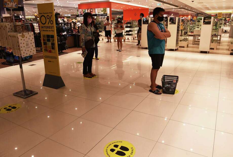 Customers observing social distancing measures while waiting in a line to pay a cashier at a mall Photo: Getty Images / AFP or licensors