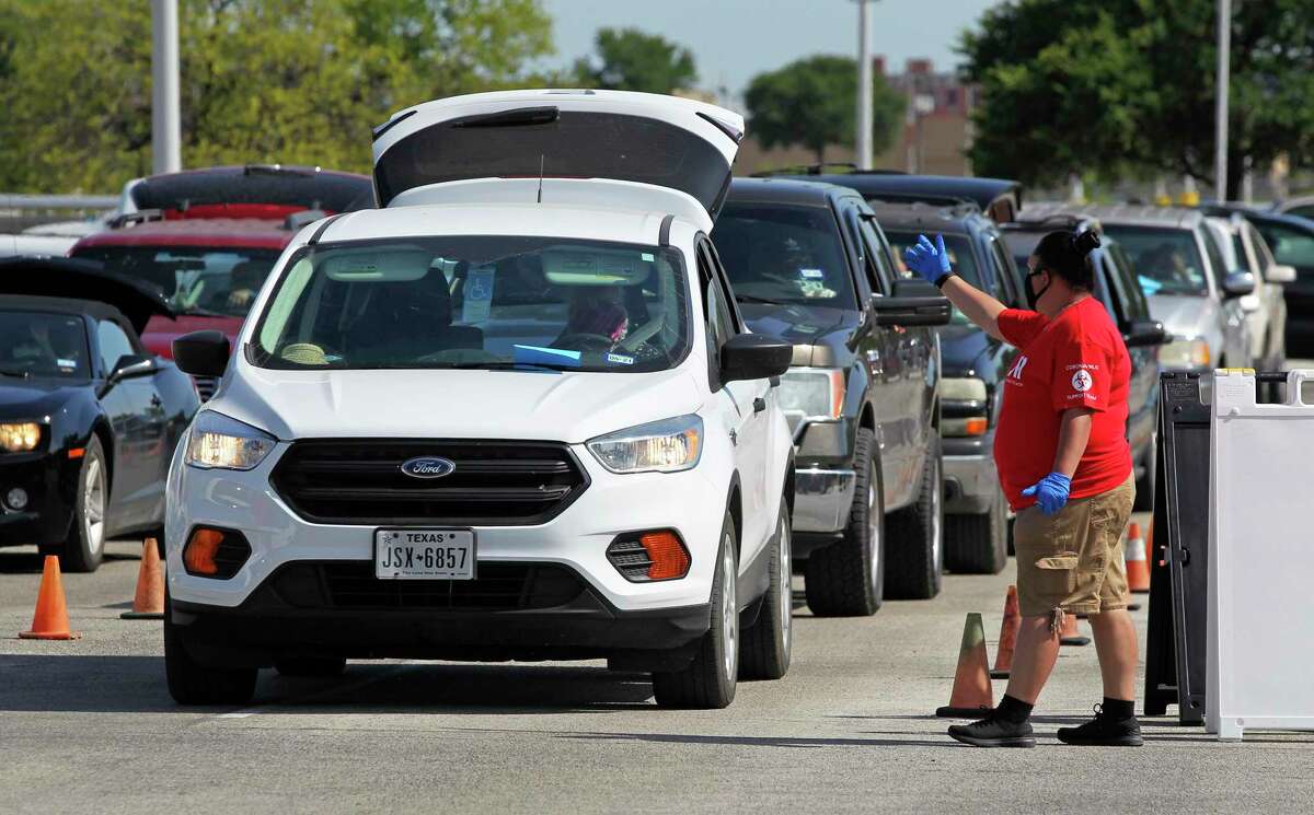 Volunteers direct lines of traffic into the scene as U.S. Sen. John Cornyn helps the Food Bank distribute groceries at the Alamodome on May 29, 2020.