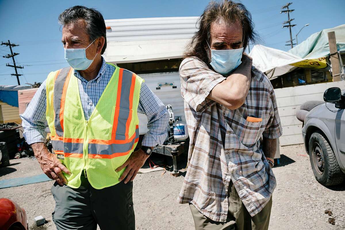 Oakland city council member Noel Gallo, left, talks with Gilberto Gonzales, who lives at the High Street Homeless Encampment in Oakland, Calif, on Thursday, May 28, 2020. Gallo said 12 recent cases of Covid-19 have been linked to the encampment through contact tracing.