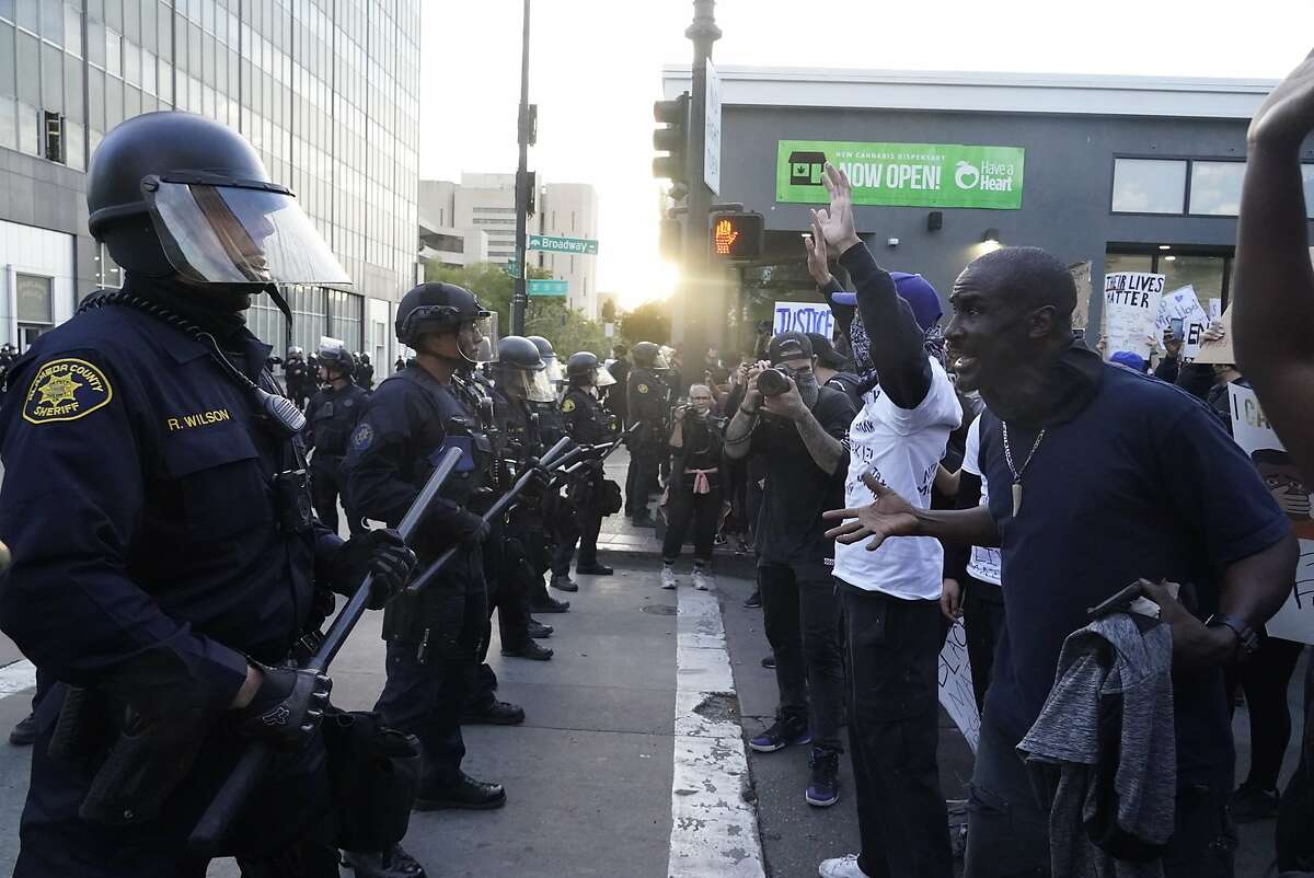 Protestors confront a police line protecting the Oakland Police Department building on 7th St. and Broadway as they protest the killing of George Floyd by police in Minneapolis on Friday, May 29, 2020, in Oakland, Calif.