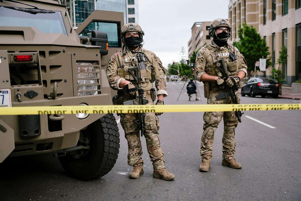 FBI agents stand behind a police line where they are investigating the shooting death of a federal protective services agent, following overnight George Floyd protest in Oakland, Calif, on Saturday, May 30, 2020.