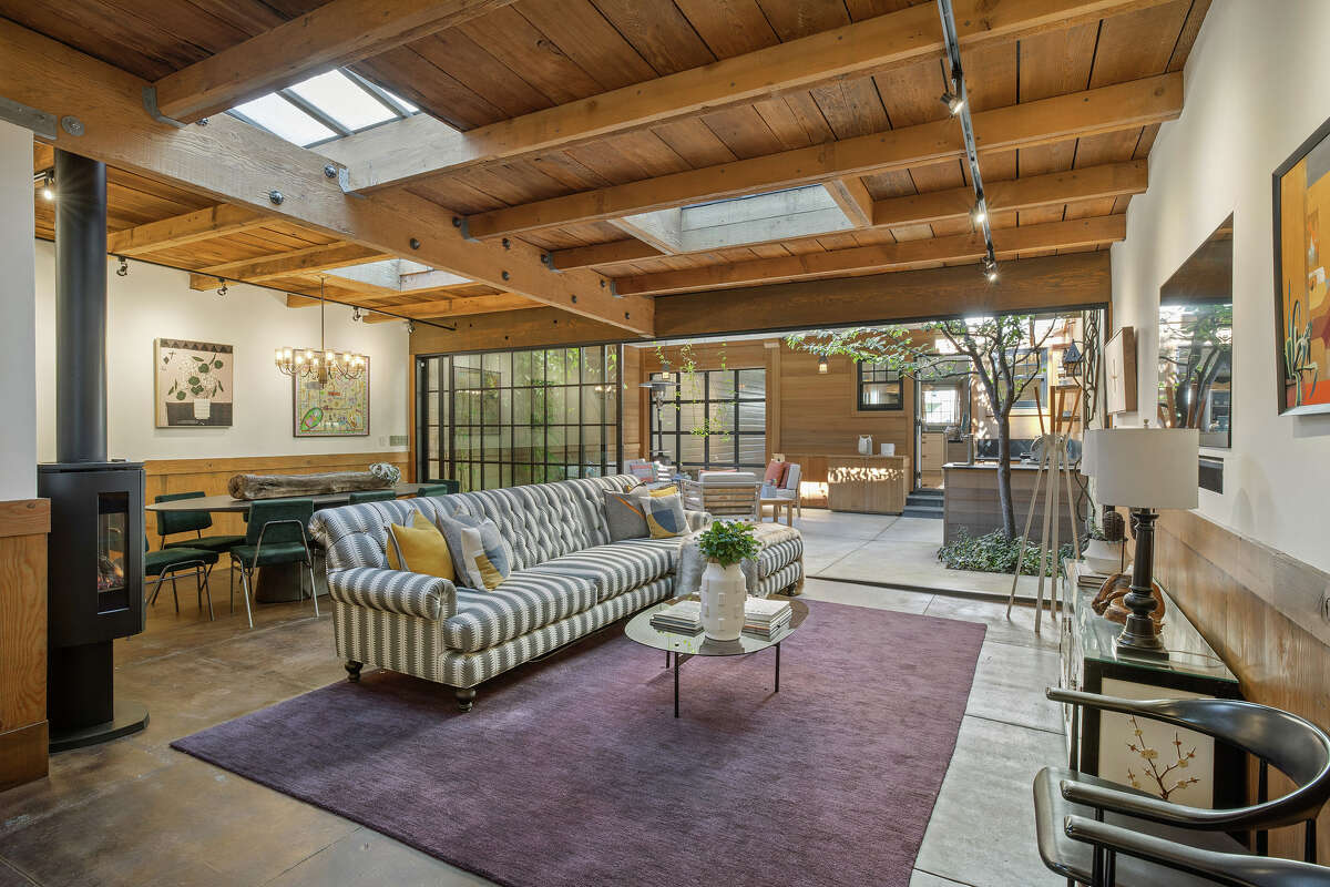 The house itself is 2,345 square feet, but feels even larger thanks to its artful remodeling. A standing gas fireplace and skylights warm the lower level living space. It features custom millwork, natural materials, concrete floors, wood-beamed ceilings, and a wall of glass that opens to the garden patio.