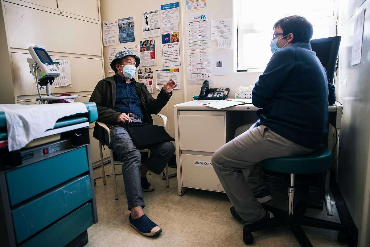 Gene Qin, 72, who tested positive for the COVID-19 novel coronavirus from his vacation aboard the Grand Princess cruise ship in early March, left, speaks during a baseline visit with Dr. Michael Peluso to participate in UCSF's Long-term Impact of Infection with Novel Coronavirus (LIINC) study to better understand the virus' effect on the human body after recovery, at the Zuckerberg San Francisco General Hospital and Trauma Center in San Francisco, Calif. on Friday, May 22, 2020.
