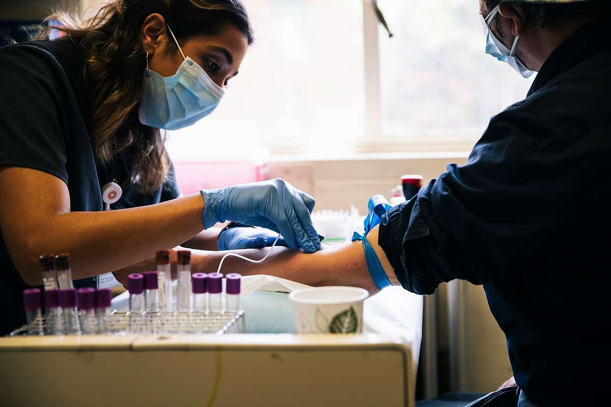 Tamareh Abualhsan, a UCSF clinical research coordinator, taking a blood sample from a coronavirus patient in May 2020.