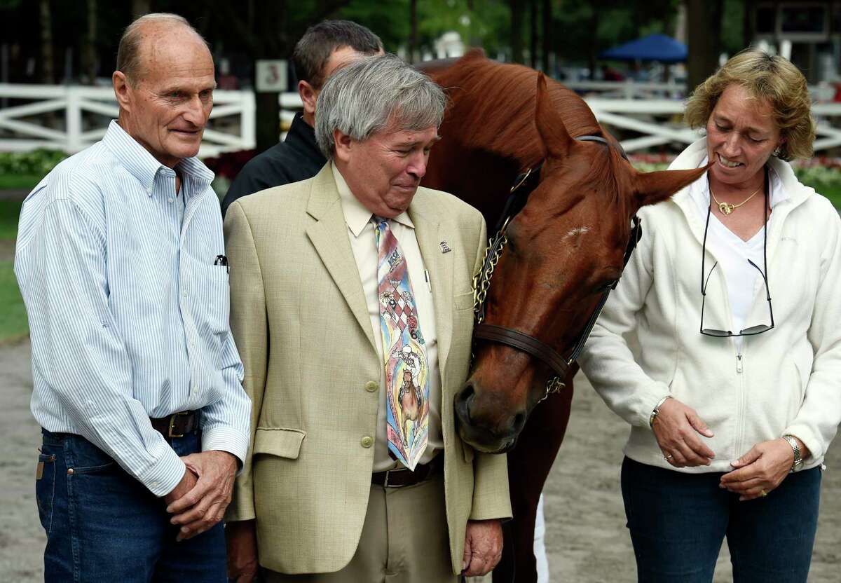 2003 Kentucky Derby and Preakness winner Funny Cide is joined by trainer Barclay Tagg, left, Sakatoga Stables managing partner Jack Knowlton, center, and assistant trainer Robin Smullen as he makes an appearance in the paddock the day before the New York Bred Showcase Day Thursday afternoon, Aug. 27, 2015, at Saratoga Race Course in Saratoga Springs, N.Y. Funny Cide was looking for mints in Knowton's jacket during the photo session. (Skip Dickstein/Times Union)