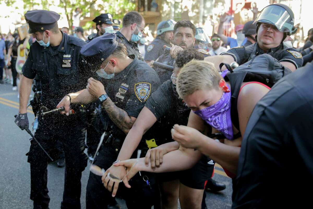 New York Police officers use pepper spray on protesters during a demonstration Saturday, May 30, 2020, in the Brooklyn borough of New York. Protests were held throughout the city over the death of George Floyd, a black man who was killed in police custody in Minneapolis on Memorial Day. (AP Photo/Seth Wenig)