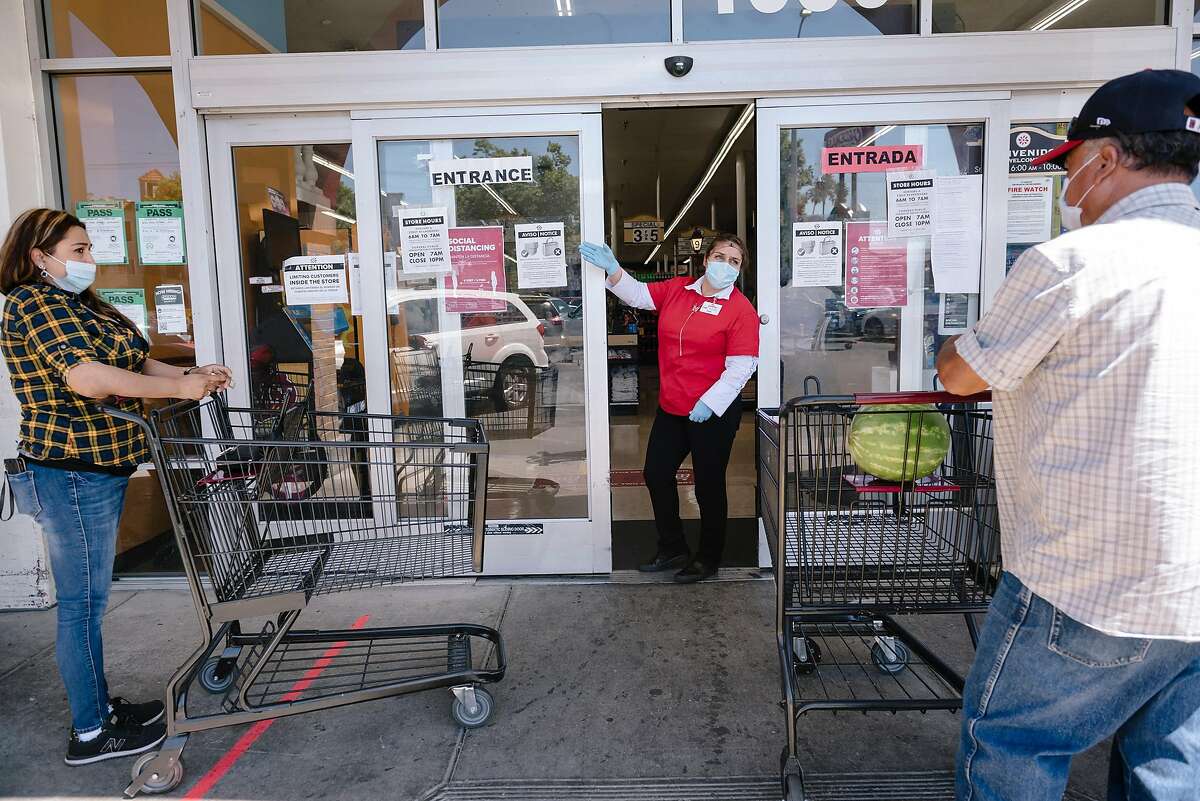 An employee directs customers to wait in line before entering a Cardenas Market in the Fruitvale District of Oakland, Calif, on Thursday, May 28, 2020. 12 employees of Cardenas Market on High Street recently tested positive for Covid-19 as Alameda County passed Santa Clara County as the hardest hit county in the Bay Area by the novel coronavirus as the East Bay community wrestled with a recent surge in cases that public health officials can't yet explain.