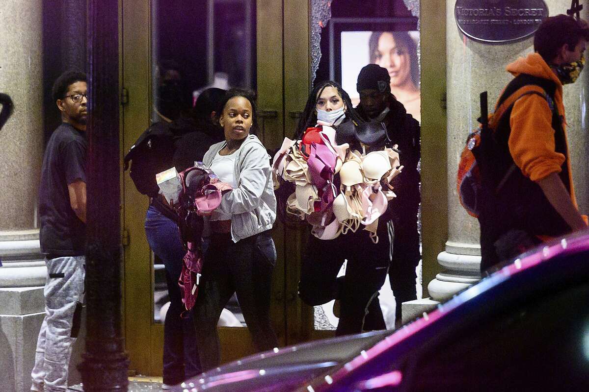Women carry merchandise from a Union Square Victoria's Secret store in San Francisco on Saturday, May 30, 2020.