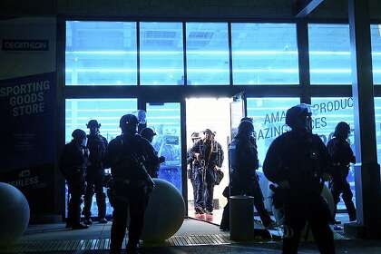 Police officers leave a damaged Decathlon sporting goods store in Emeryville on Saturday after widespread vandalism during the George Floyd protests.