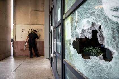 Missael, an employee at Yard House, cleans off graffiti that reads ÒFire Fauci,Ó next to a damaged window in downtown San Antonio, Texas, U.S. on Sunday, May 31, 2020 following violent protests the previous night. The day followed a night of protests in downtown San Antonio where business frontÕs were damaged and some businesses were looted. Saturday saw hundreds of people gather in downtown San Antonio to protest the death of George Floyd in Minnesota while he was in police custody.