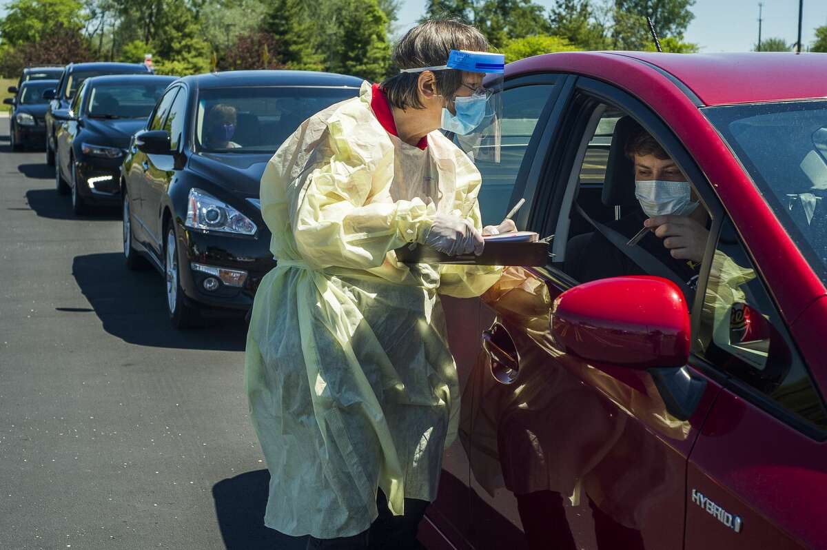 Dr. Catherine Bodnar of the Midland County Health Department takes down information from Andrew Bott before he receives a COVID-19 test at a free drive through testing clinic, open for the second day in a row, Sunday, May 31, 2020 at Dow Diamond. (Katy Kildee/kkildee@mdn.net)