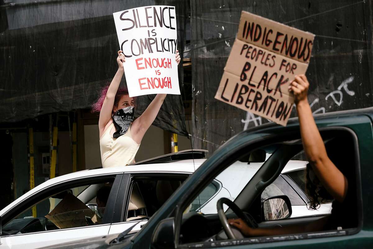 Protestors hold up signs during a Justice for George Floyd & Breonna Taylor Car Caravan in Oakland, Calif, on Sunday, May 31, 2020.