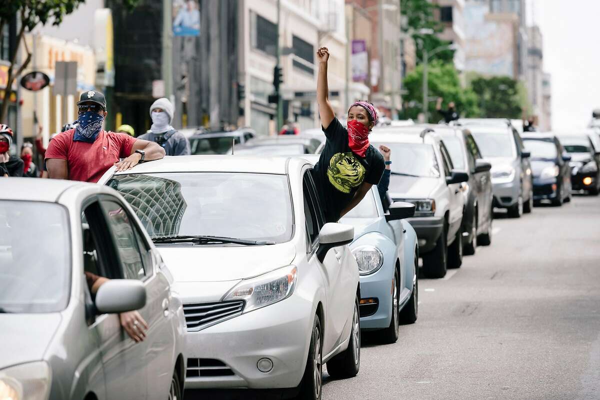 People raised their fists from their cars during a Justice for George Floyd & Breonna Taylor Car Caravan in Oakland, Calif, on Sunday, May 31, 2020.