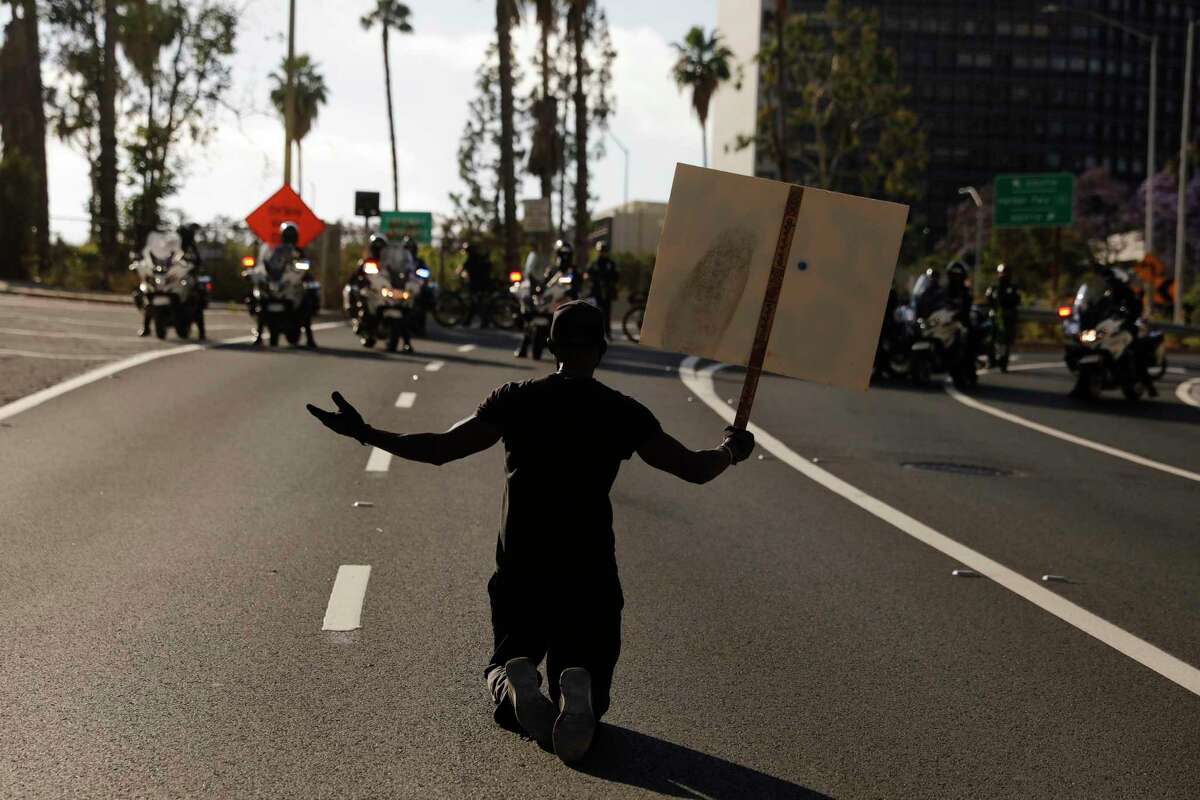 A man kneels on the street in front of police officers while chanting "I can't breathe" during a protest over the death of George Floyd, Friday, May 29, 2020, in Los Angeles. Floyd died Memorial Day while in police custody in Minneapolis. (AP Photo/Jae C. Hong)