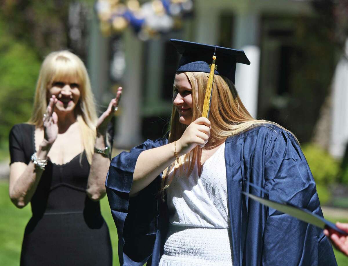 New graduate Lauren Garrigues moves her tassel from one side to the other as members of King School faculty perform a drive-thru commencement at her home in Stamford, Conn. Sunday, May 31, 2020.