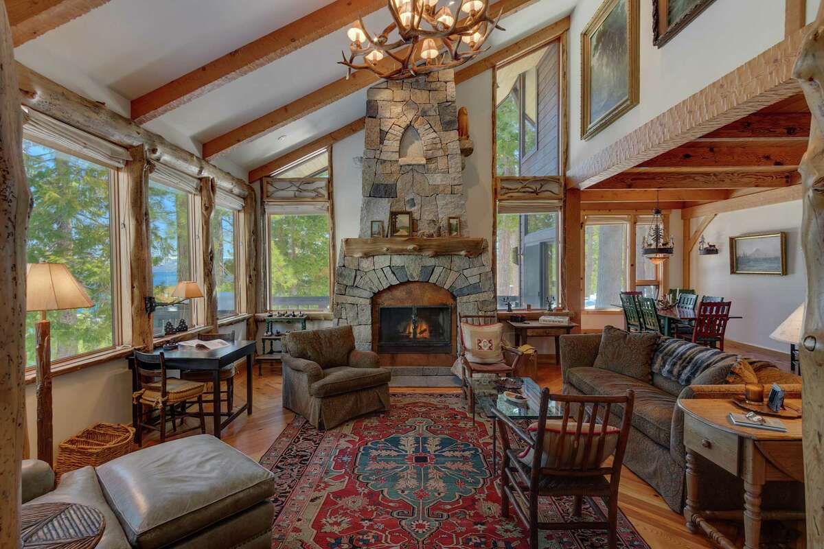 The living room features a vaulted ceiling, a multitude of windows and a stone fireplace.