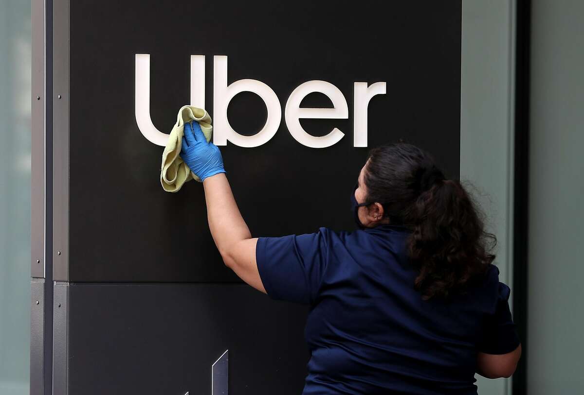 A worker cleans a sign in front of Uber headquarters on May 18, 2020, in San Francisco.