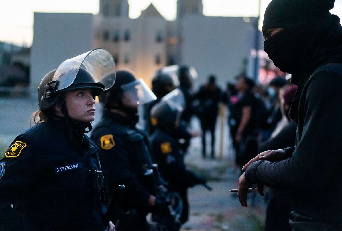 Berkeley Police Officer S. Speelman listens to a person protesting the killing of George Floyd by Minneapolis police on Sunday, May 31, 2020 in Oakland.
