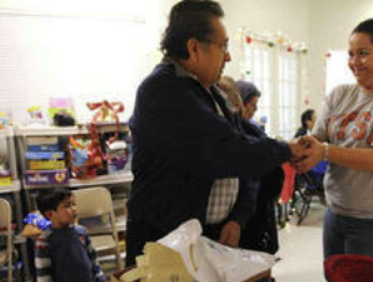 Gonzalo M. Garza shakes the hand of Elizabeth Rodriguez, Merced Housing's resident services coordinator, after receiving food Friday at Merced's Avion Place Apartments.