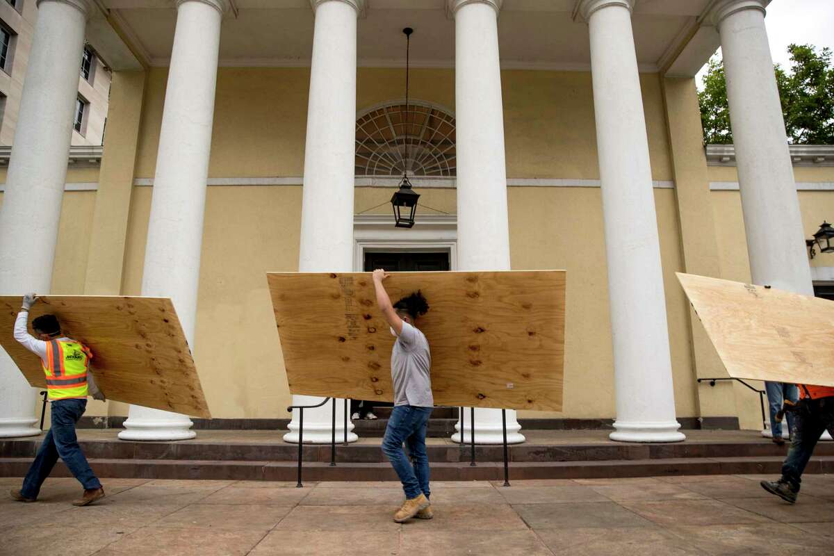 Workers carry large wood boards past the historical St. John's Episcopal Church across Lafayette Park from the White House in the morning hours in Washington, Tuesday, June 2, 2020, as protests continue over the death of George Floyd. Floyd died after being restrained by Minneapolis police officers.