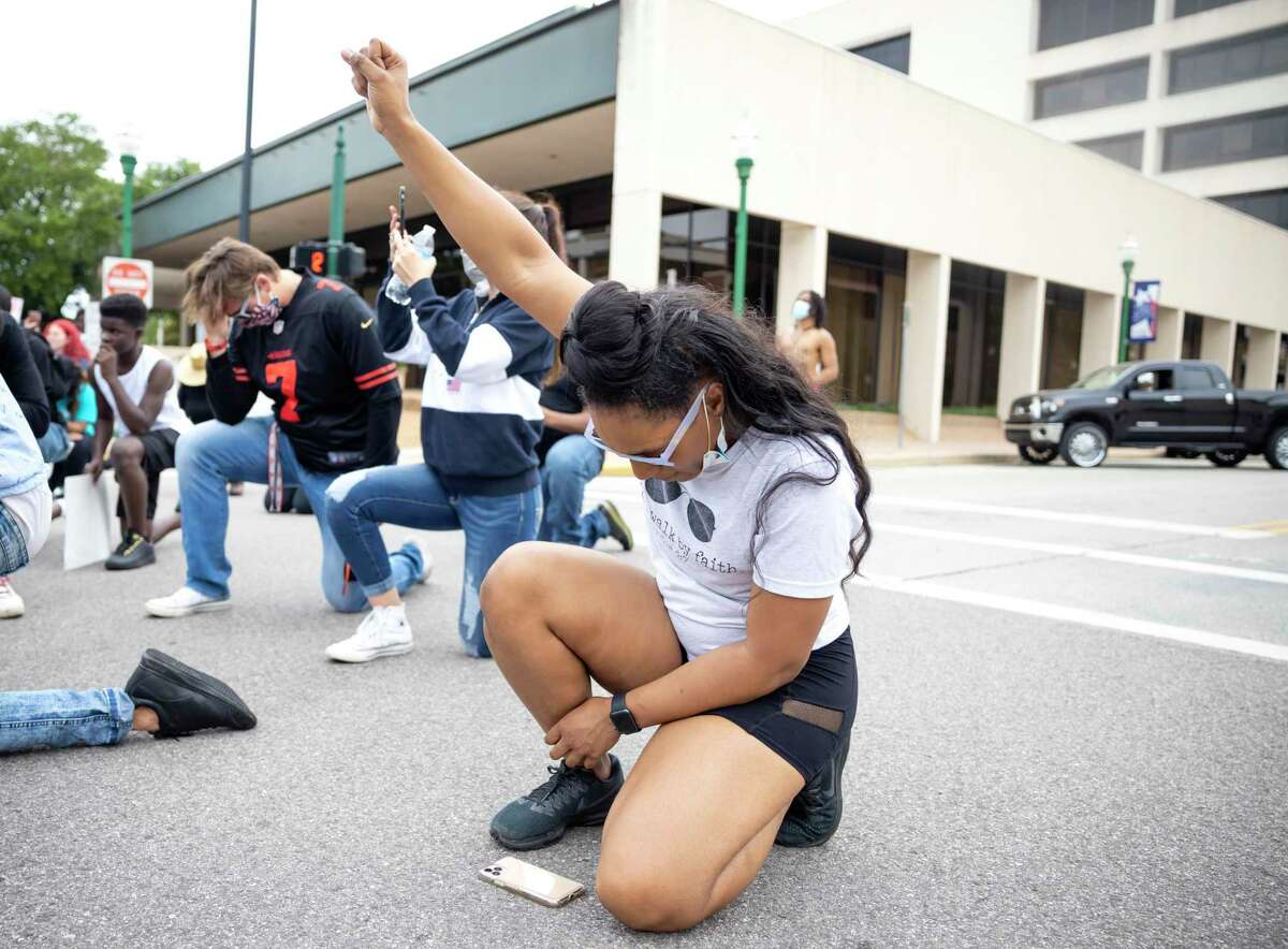 A demonstrator kneels for a moment of silence in honor of George Floyd in downtown Conroe, Sunday, May 31, 2020. Approximately over 100 people participate in the demonstration.
