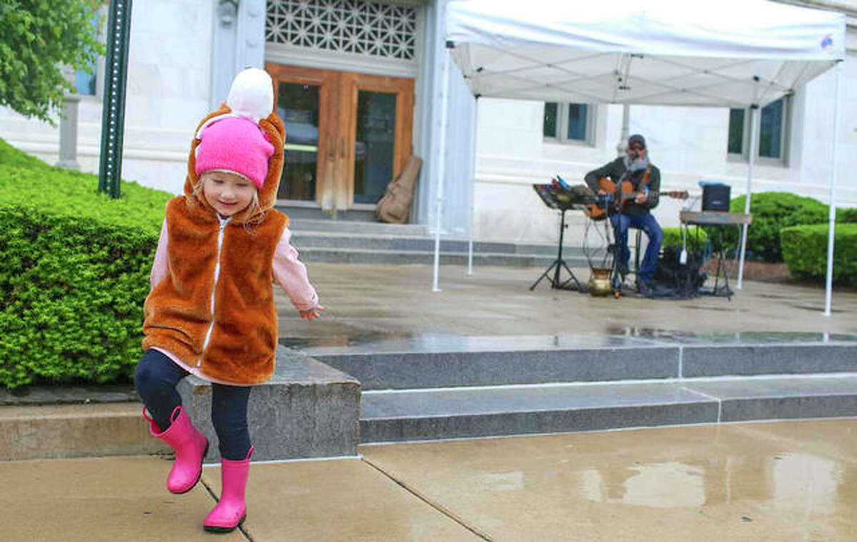 Valerie Van Daley, 4, dances and splashes in puddles while listening to local musician Butch Moore play some tunes last year at the Goshen Market in Edwardsville.