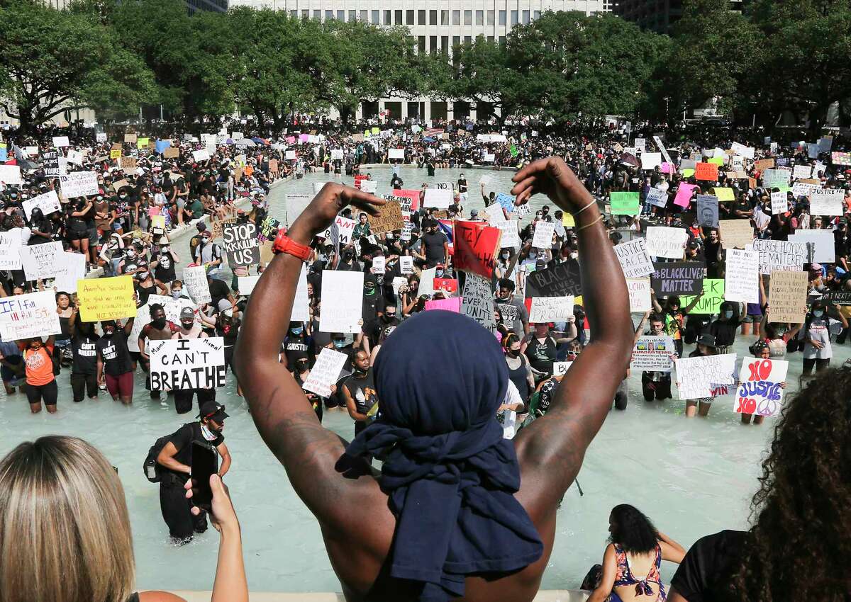 Protesters hold signs in the reflecting pool in front of Houston's City Hall as they listen to speeches after a march in honor of George Floyd on Tuesday, June 2, 2020.