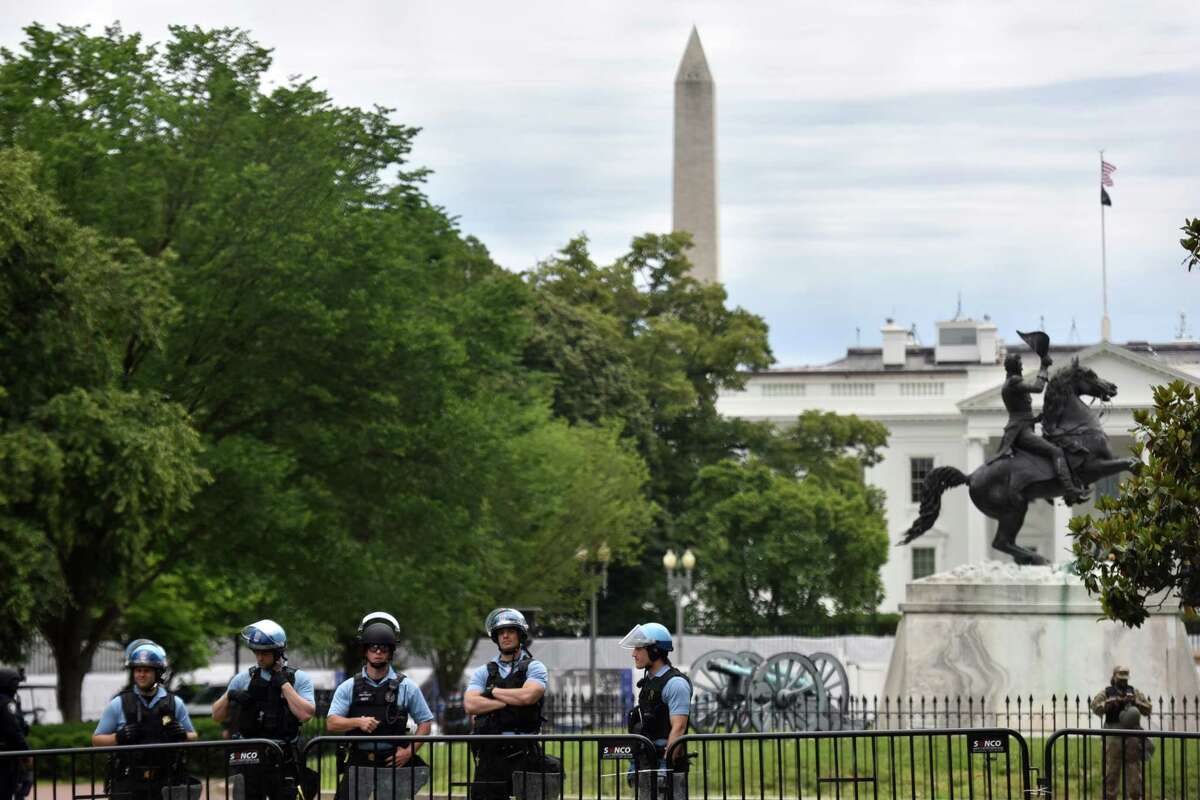 Authorities stand guard behind a large fence as dozens of protesters rally outside of Lafayete Square in Washington, D.C., on Tuesday.